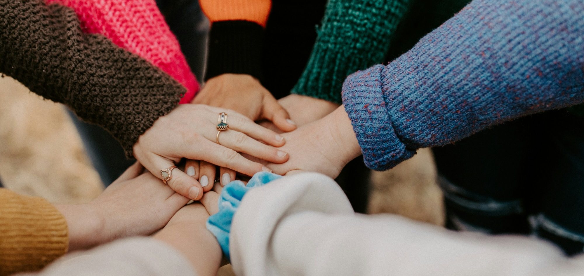 A diverse group of hands stacking on top of each other in unity.